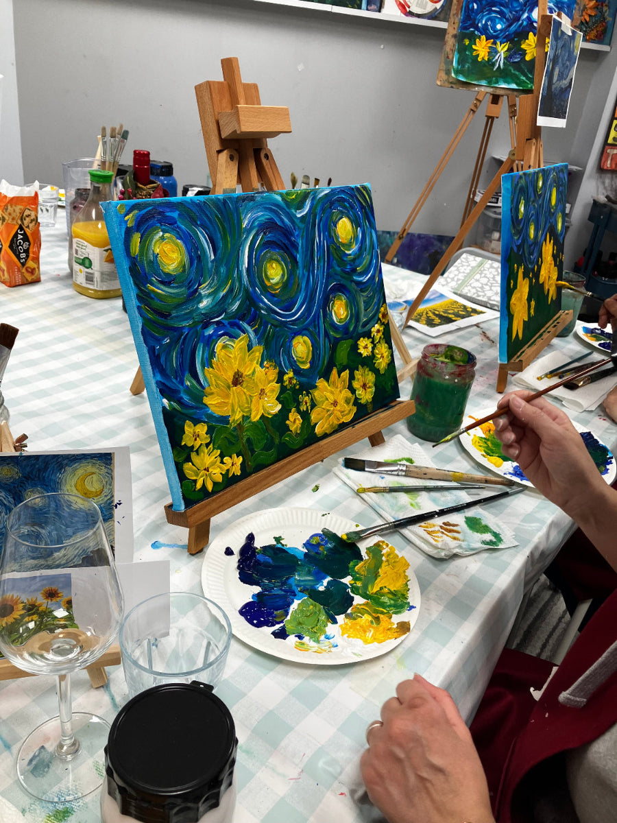 Artistic scene with a painting of 'Starry Night' and various art supplies on a table.