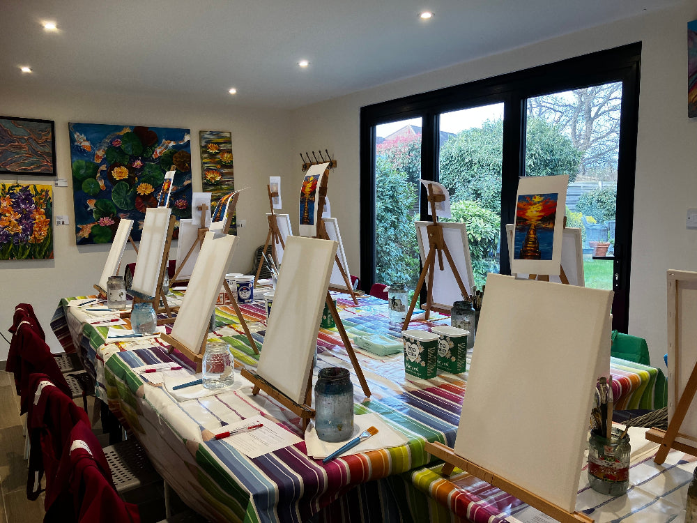 Art studio with tables set up for painting, easels, and art supplies.