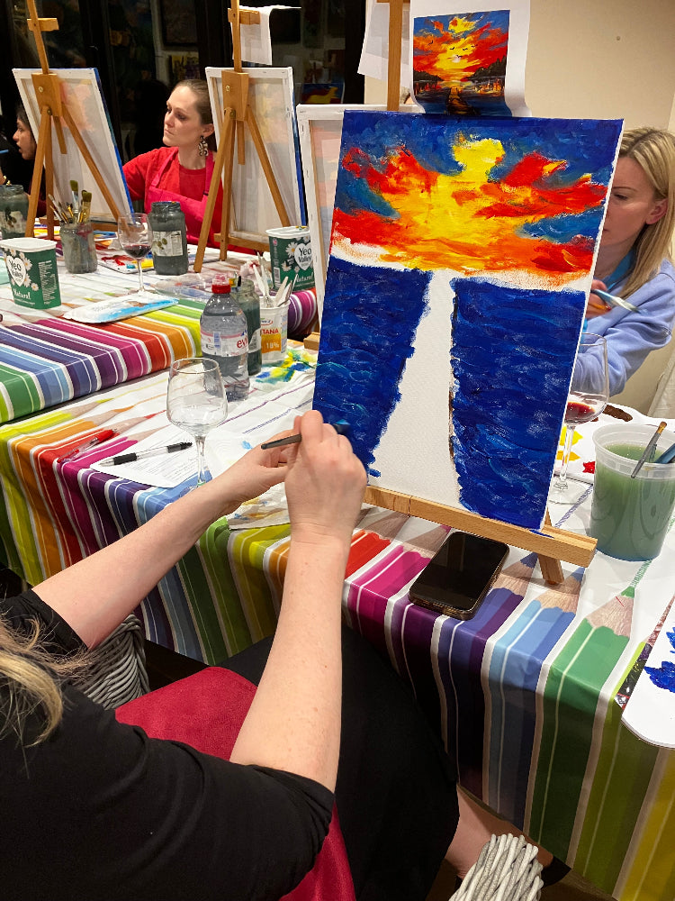 Person painting a colorful abstract artwork with various art supplies around.