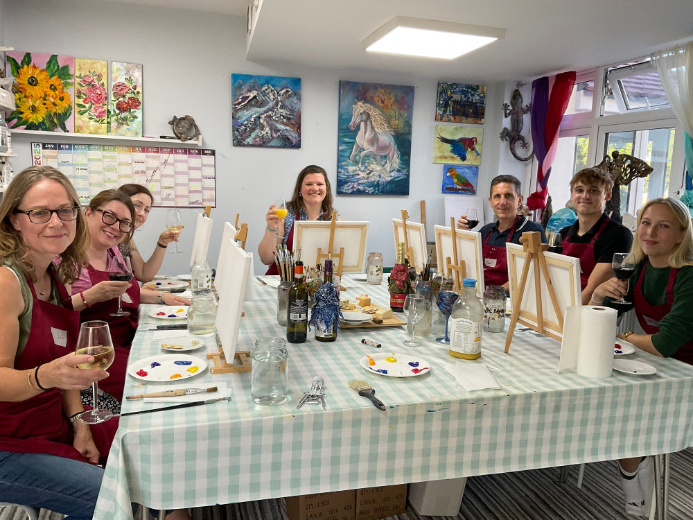 Artistic setup with paintings, brushes, and a checkered tablecloth.