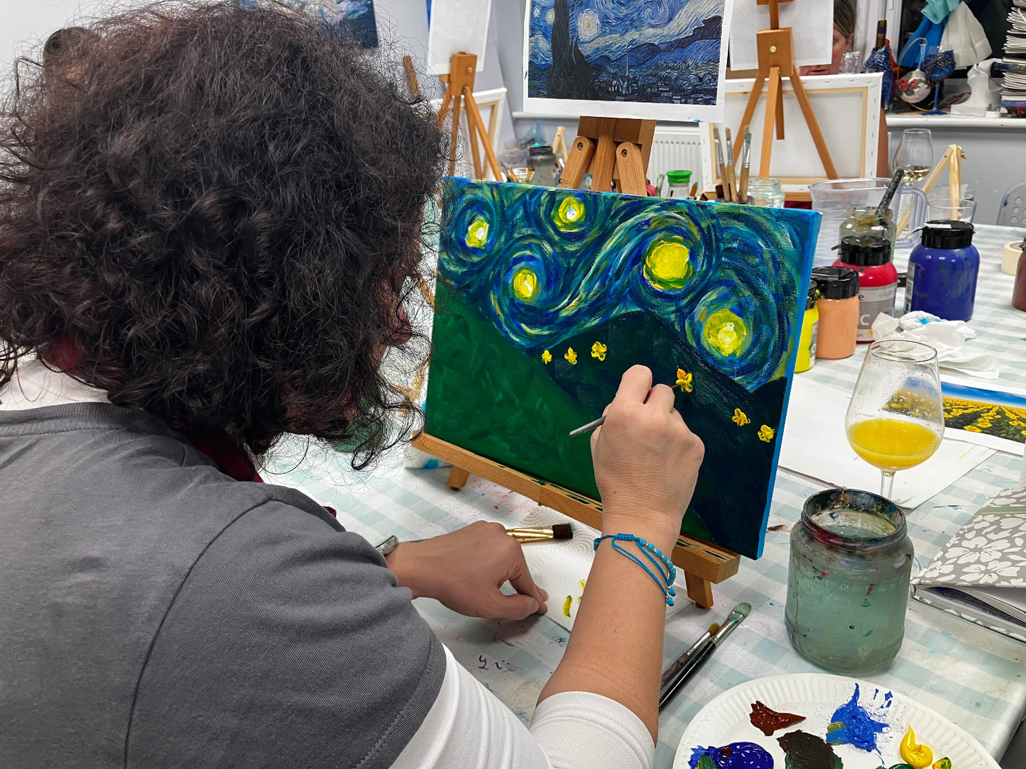 Person painting 'Starry Night' on an easel with art supplies around