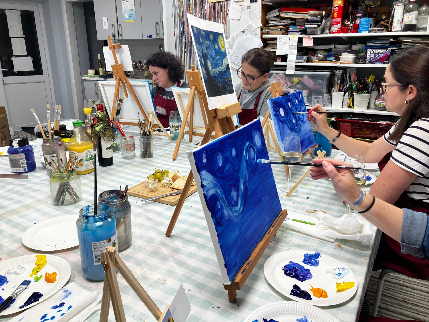 Art class in progress with students painting on easels in a studio setting.