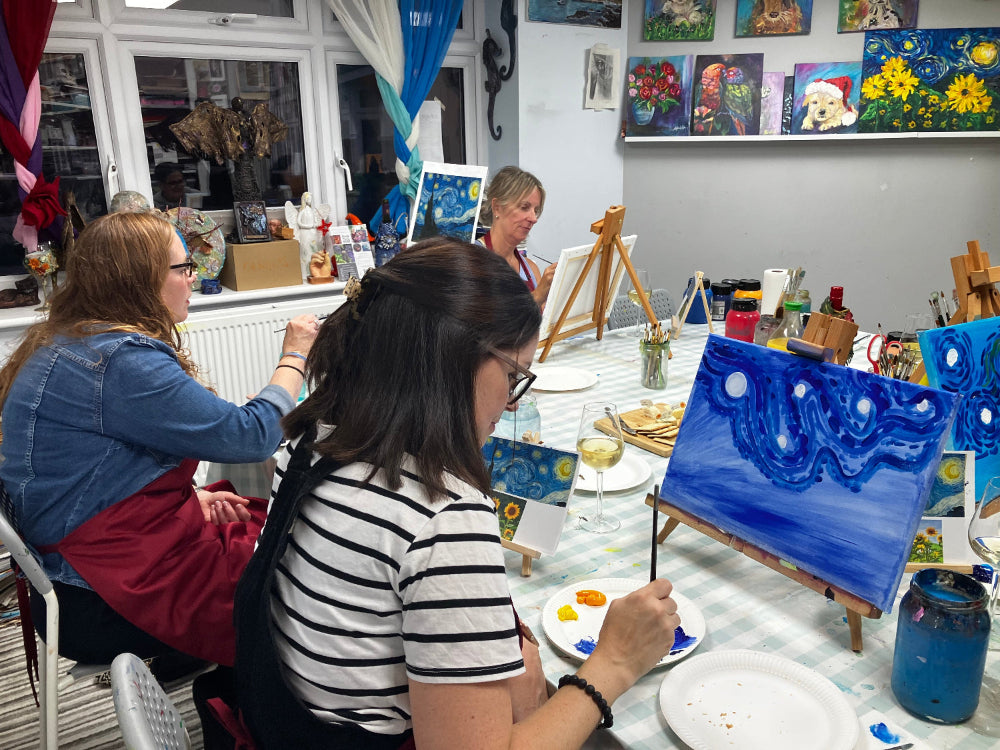Art class in progress with students painting at a table.