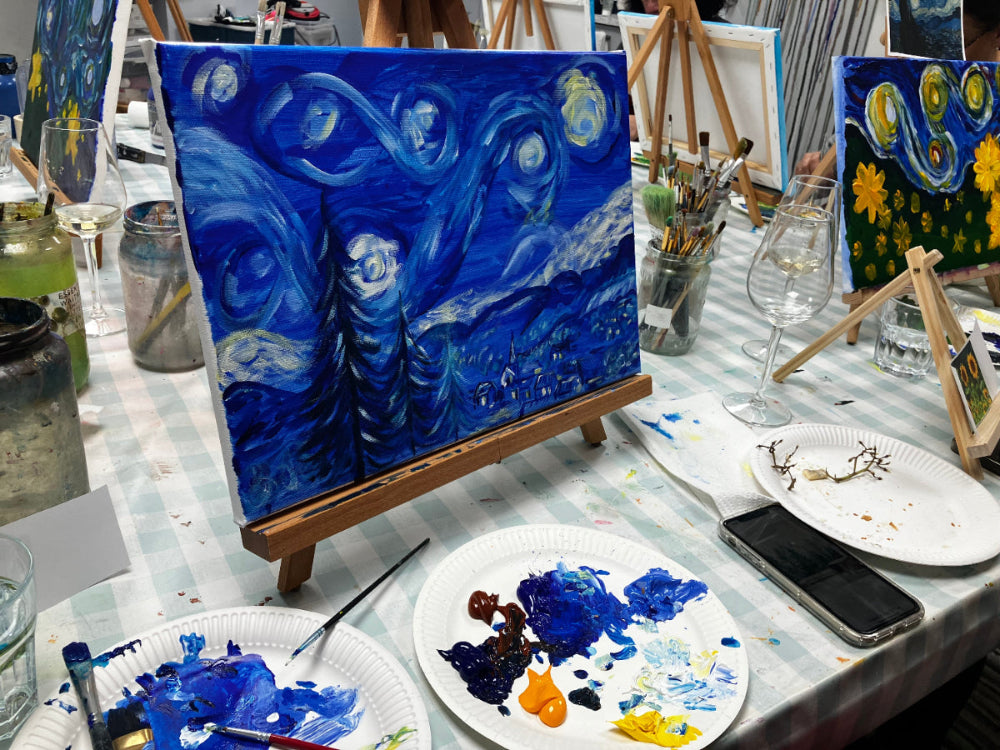 Artistic setup with a painting of 'Starry Night' on an easel, paint palette, and various art supplies.